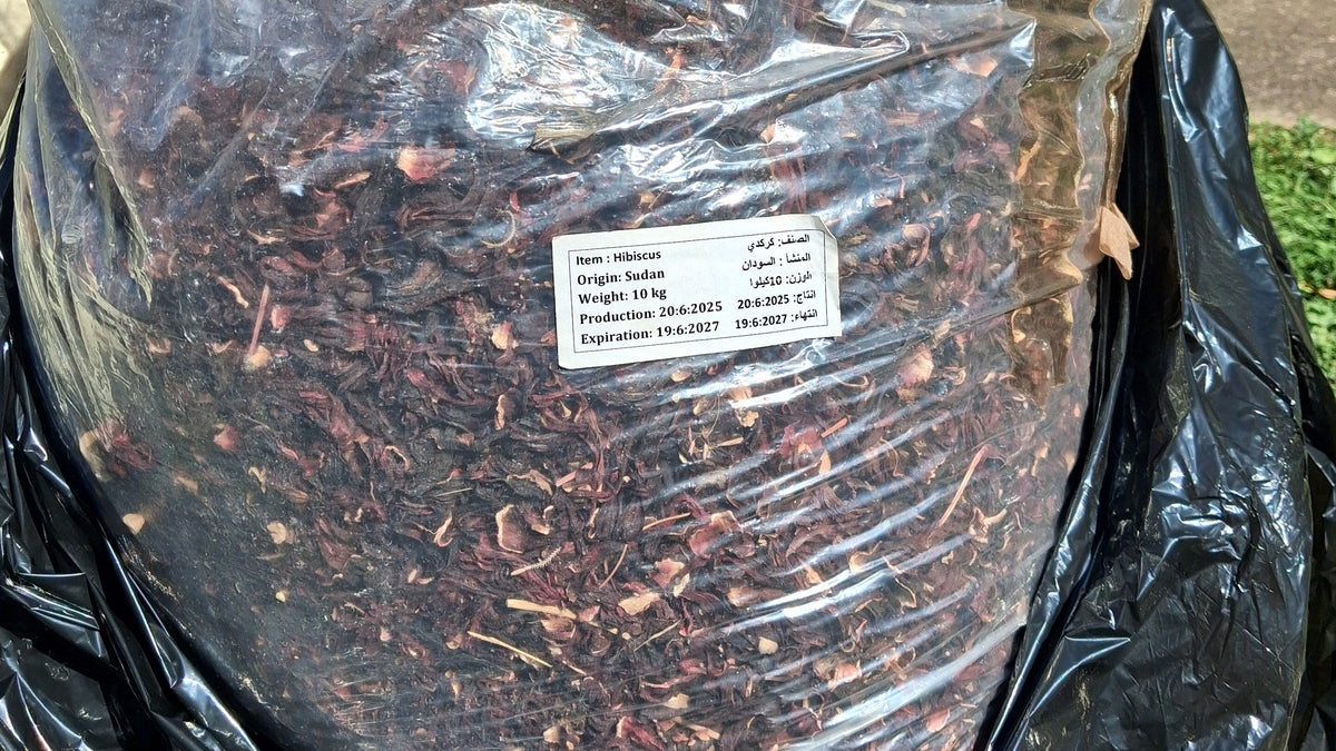 A 10kg bag of whole dried karkade hibiscus with a label reading Origin: Sudan.