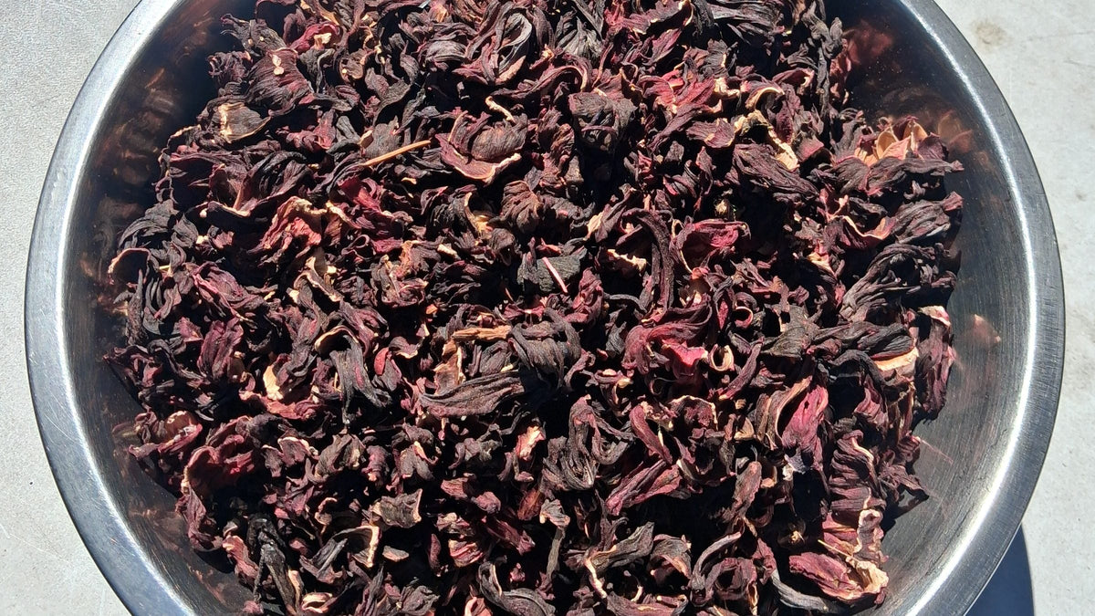 A steel bowl full of whole dried hibiscus calyces, seen from above.